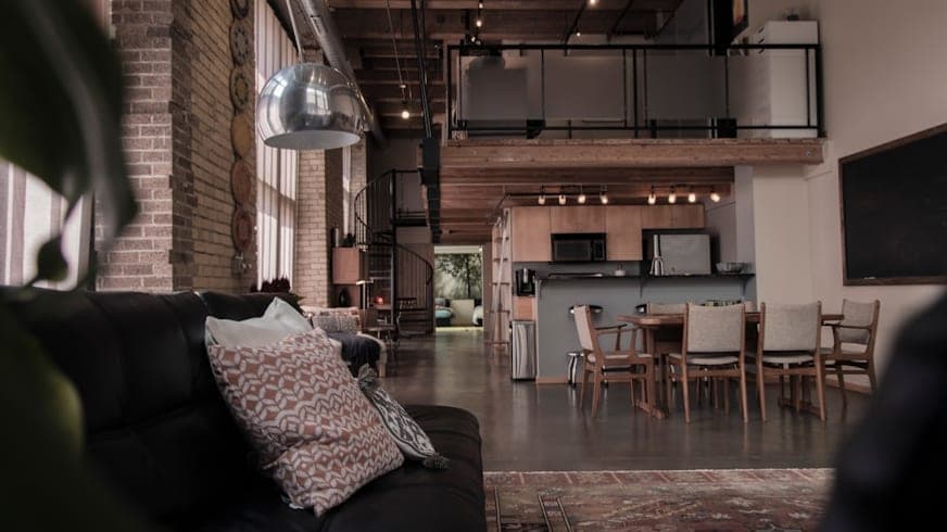 Loft living room with exposed brick, a steel mezzanine and a black leather sofa