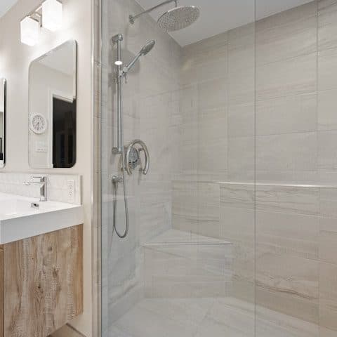 Marble-tiled walk-in shower and glazed sanitaryware in a pale bathroom