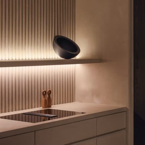 Backlit fluted oak wall panel with a shallow shelf and a black ceramic bowl