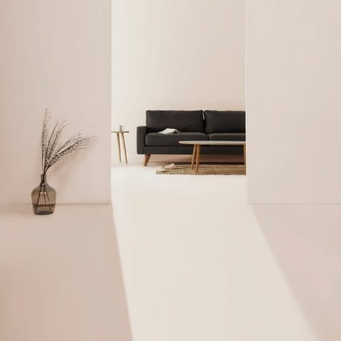 Charcoal modular sofa on slim wooden legs in a bright white room with a plaster arch