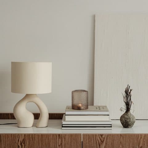 Travertine-toned surface with a stack of books and a ribbed glass votive