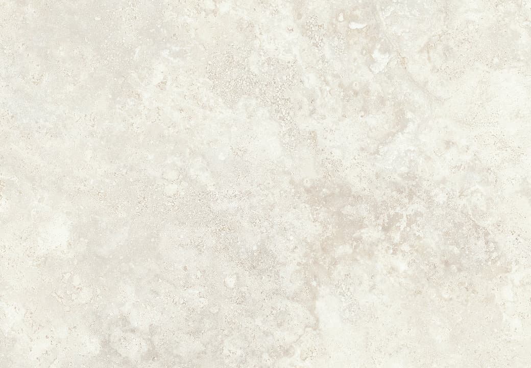 Pearly cross-cut travertine wall behind a shallow stone basin, lit from the side so the bedding planes read as horizontal veining