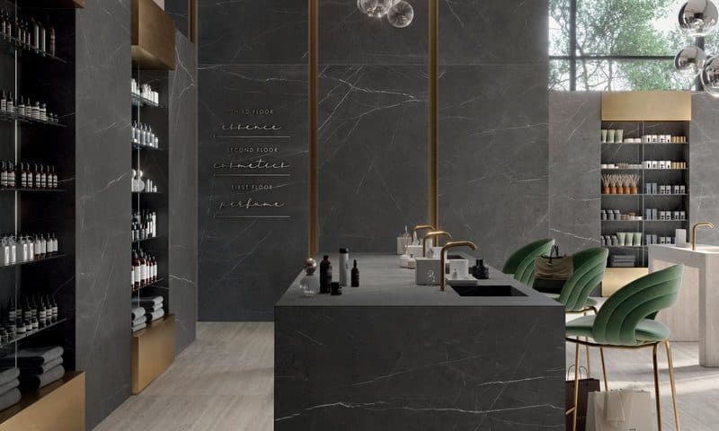 Apothecary-style interior with a dark marble island, brass shelving and green planting