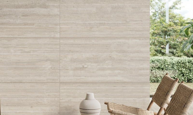 Banded pale travertine wall tiles beside a rattan chair and a white vessel outdoors