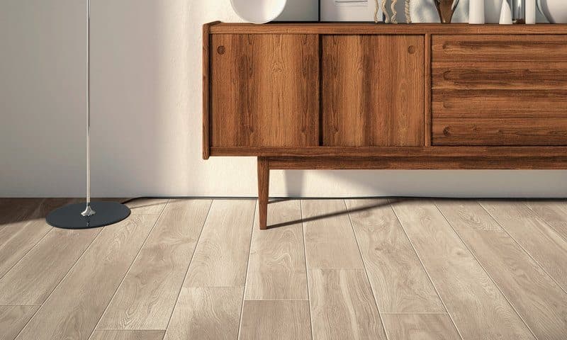 Walnut sideboard on slender legs against a white wall, over a pale wood-effect floor