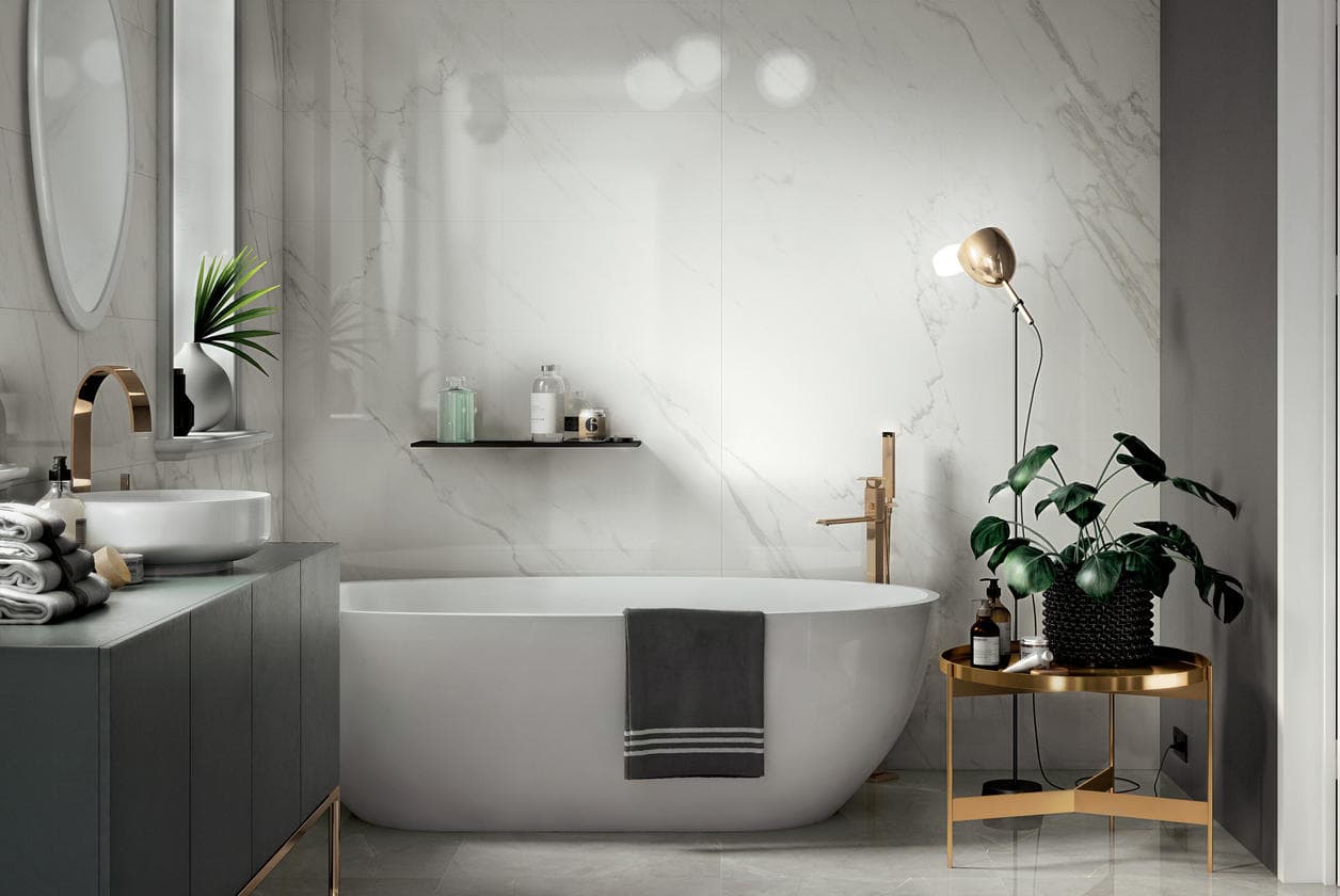 Statuario marble bathroom with a freestanding oval bath, a slim floor lamp and a potted plant