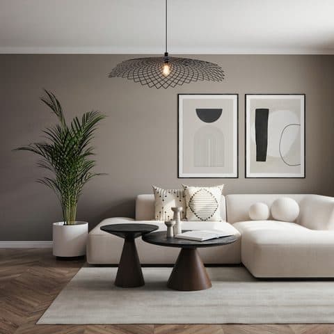 Woven pendant light over a low table in a warm grey living room with two framed prints