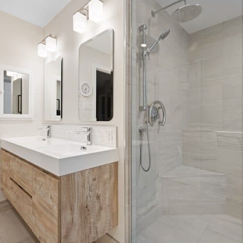 Pale oak vanity unit with a white solid-surface basin top, under two rectangular mirrors