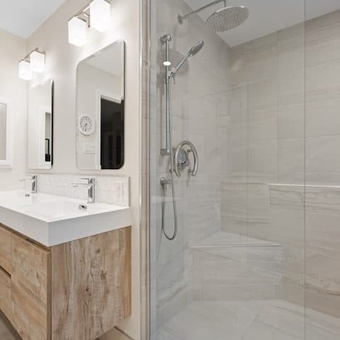 Walk-in shower with a low stone-textured tray and a brushed steel column
