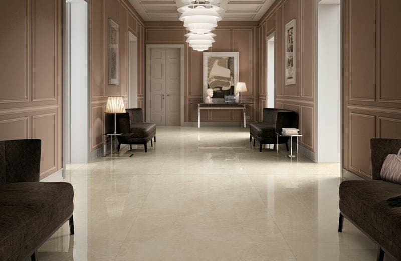Long panelled hallway in dusty pink with polished cream marble-effect floor tiles, armchairs and a tiered pendant light