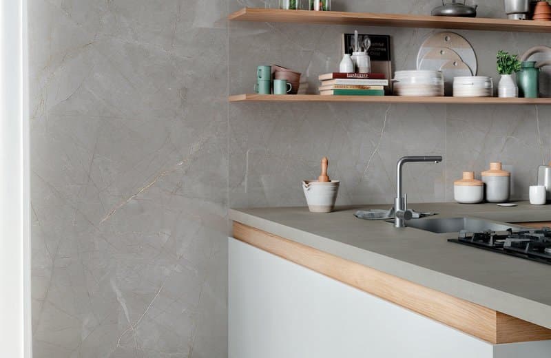 Grey marble-effect kitchen splashback and island top with oak open shelving, a steel sink and a gas hob