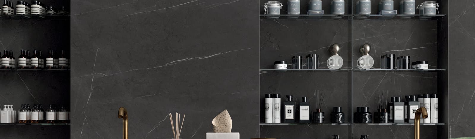 A dark marble bathroom wall with open shelving of bottles and jars, lit low and warm